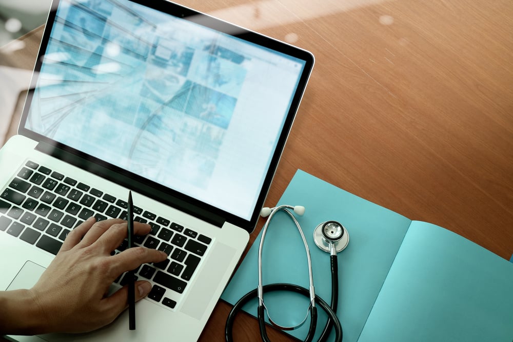 top view of Medicine doctor hand working with modern computer and smart phone on wooden desk as medical concept top view of Medicine doctor hand working with modern computer and smart phone on wooden desk as medical concept